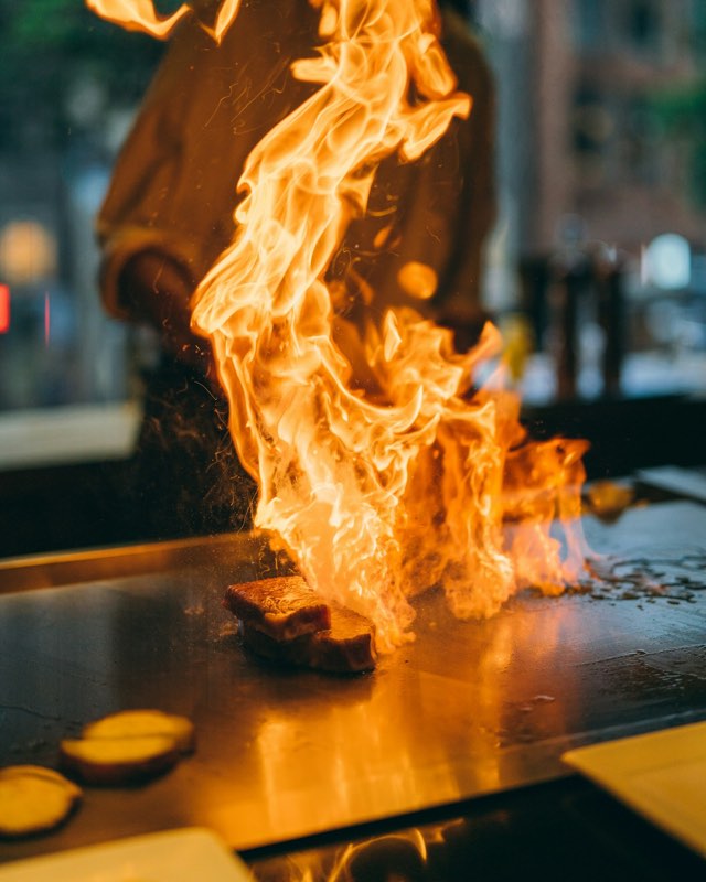 Steak searing in tall flames on the hibachi grill